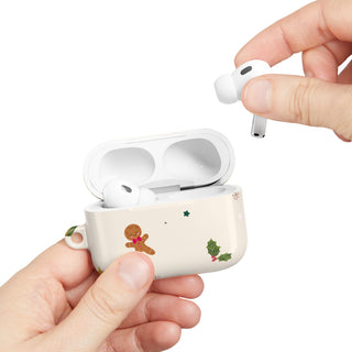 White wireless earbuds in a case with Christmas-themed designs held by hands against a white background