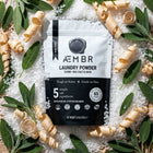Non-toxic laundry detergent powder pouch with sage leaves, salt, and wood shavings.