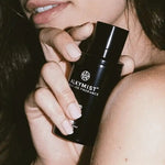 Woman holding Alkymist fragrance bottle by AEMBR, close-up, natural beauty