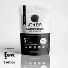 AEMBR non-toxic laundry powder pouch with branding, eco-friendly badges, and 'As Seen On E! News, Forbes'