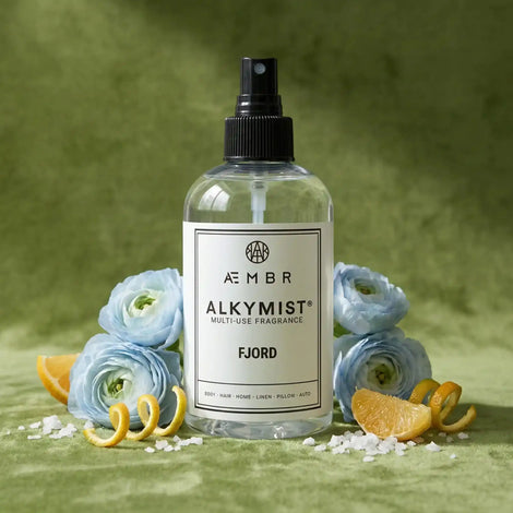 Non-toxic multi-use fragrance spray with blue flowers, citrus slices, and sea salt on green background