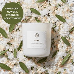 Candle labeled 'FJORD' on a textured surface with green leaves and text about scent strength.