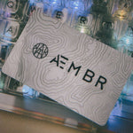 AEMBR branded card with topographic design on illuminated mechanical keyboard background