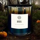 AEMBR HEKS luxury scented candle with Dragon's Blood & Sandalwood, outdoors with pumpkins