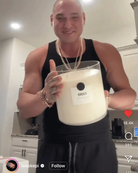 Smiling man in kitchen holding large AEMBR FLORD non-toxic candle