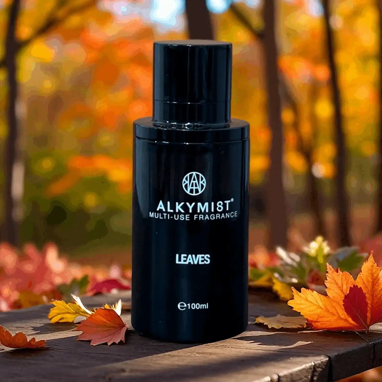 AEMBR ALKYMI8T multi-use fragrance bottle on wood table with autumn leaves and fall trees