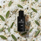 AEMBR ALKYMIST fragrance bottle on salt, wood shavings, and sage leaves, natural setting