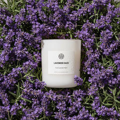 White candle labeled 'Lavender Haze' surrounded by purple lavender flowers