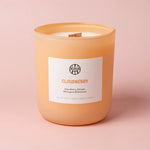 AEMBR Cloudberry scented candle in peach glass jar on soft pink background
