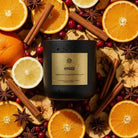 AEMBR Hygge candle in black jar with gold label, surrounded by citrus, cinnamon, and star anise