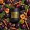 AEMBR Berry + Embers non-toxic candle in black jar, surrounded by plums, cinnamon, and cypress