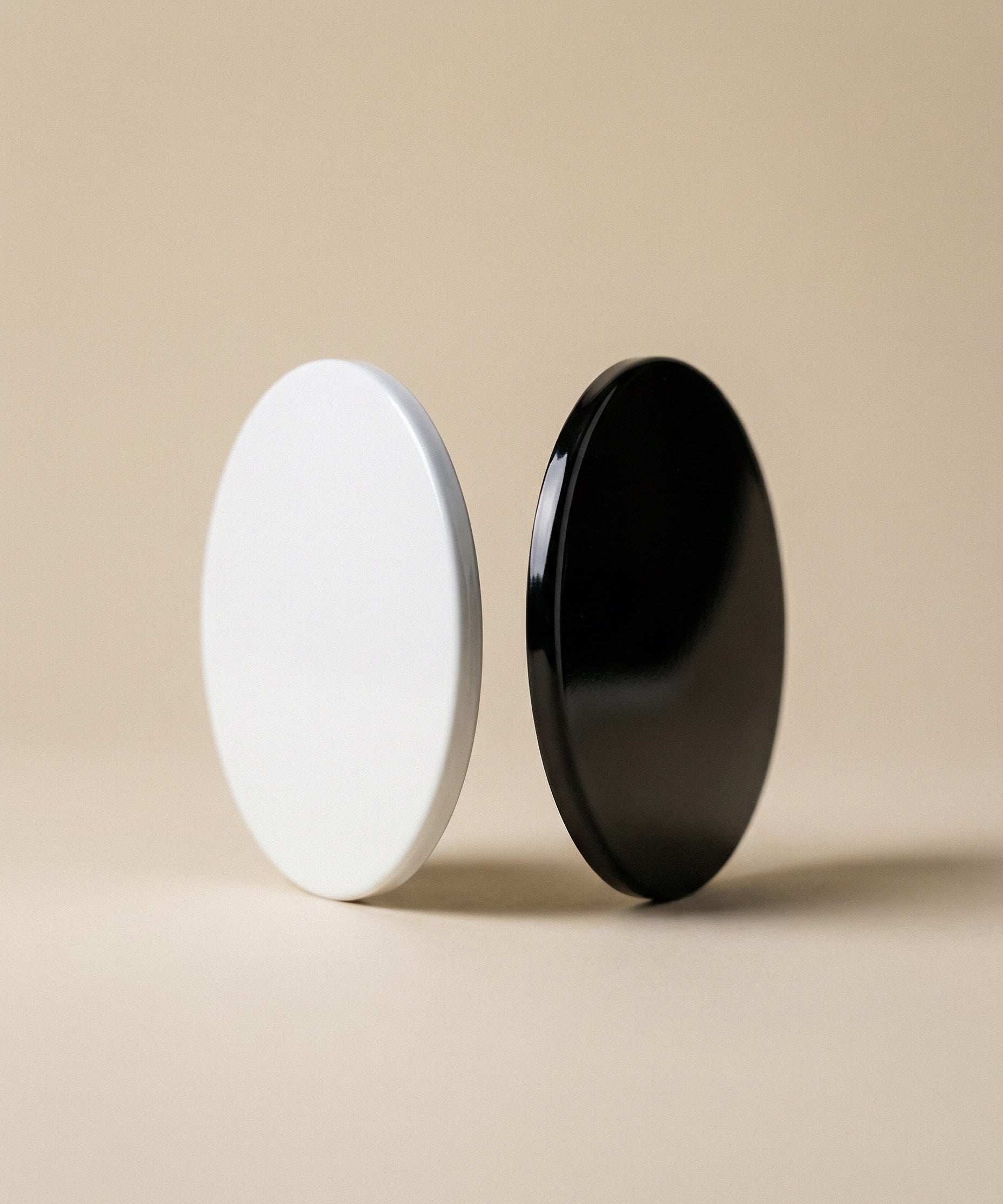 Minimalist black and white round product containers on a beige backdrop, AEMBR home essentials.
