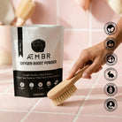 Non-toxic oxygen boost powder laundry detergent in pouch, hand using cleaning brush on tile.