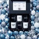 AEMBR scented candle gift set with six labeled candles in a black box, surrounded by blue and silver holiday ornaments and bows.