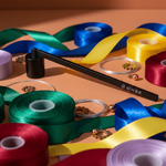 Assorted colorful ribbons and spools of thread on a peach background