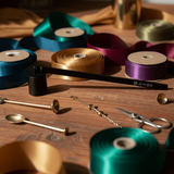 Assorted ribbons and jewelry-making supplies on a wooden surface with soft lighting.
