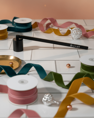 Spools of ribbon and decorative items on a white surface with a pinkish-beige background