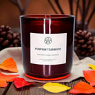 Pumpkin Teakwood non-toxic scented candle in amber glass, autumn leaves and pinecones decor