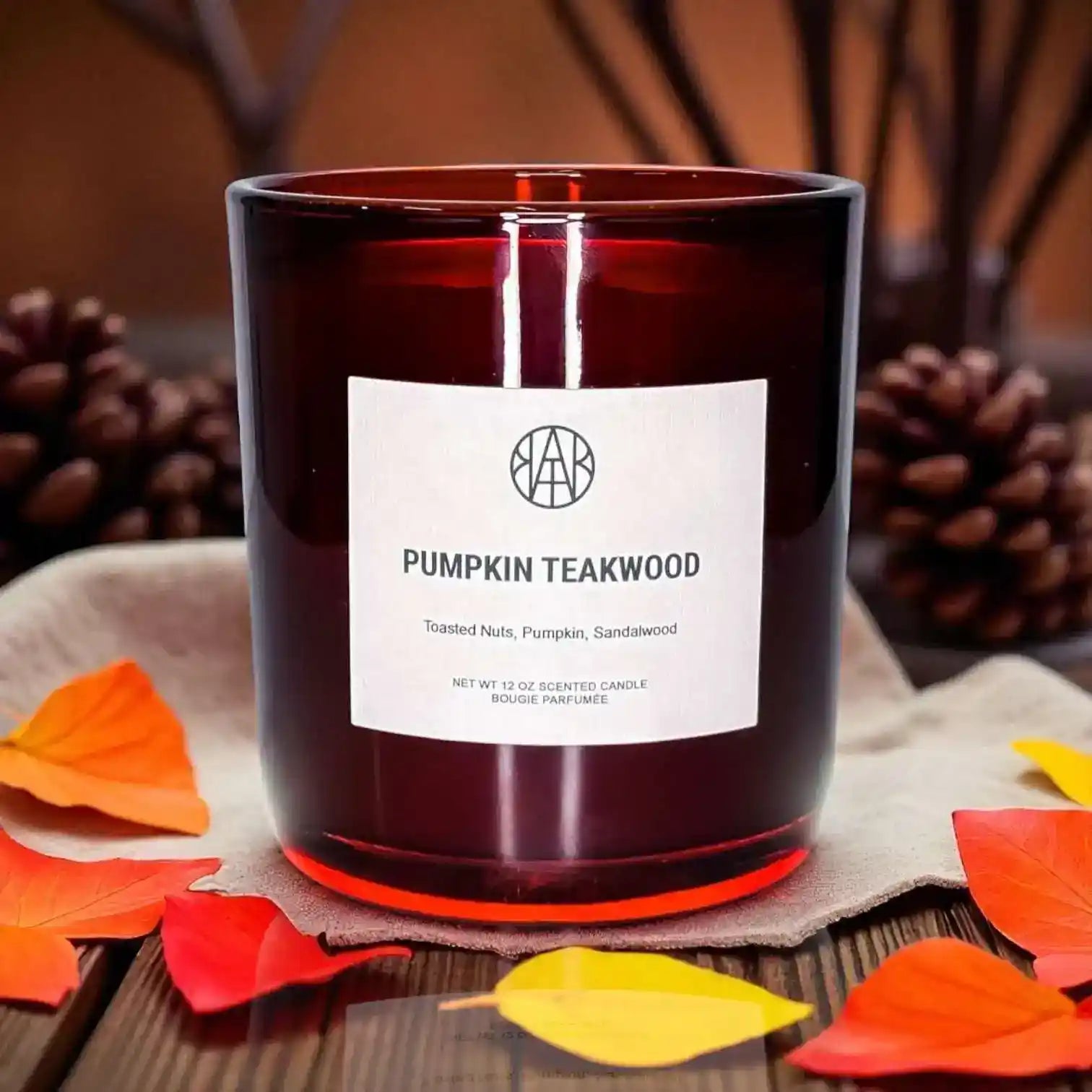 Pumpkin Teakwood non-toxic scented candle in amber glass, autumn leaves and pinecones decor