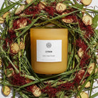 A citron-scented candle from AEMBR with a simple glass holder, emitting a warm, inviting glow.