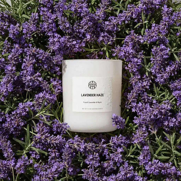 Lavender Haze Candle by AEMBR with a glass jar, showcasing a soft purple wax and a cotton wick, ideal for relaxing ambiance.