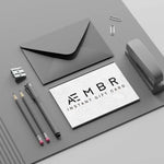 AEMBR instant gift card with envelope, pencils, pen, sharpener, stapler, and paper clips on gray desk