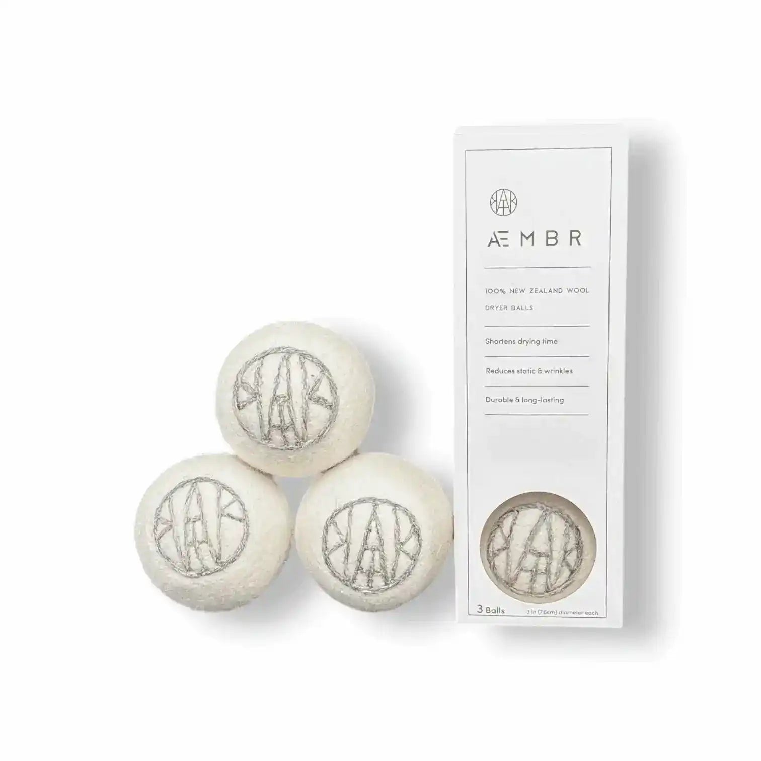Set of AEMBR wool dryer balls in natural colors, shown with laundry essentials including detergent, linen spray, and oxygen boost.