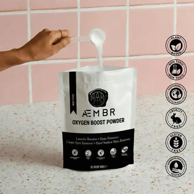 AEMBR Oxygen Boost laundry additive in a clear container with a scoop, part of the Fjord laundry bundle including dryer balls and linen spray.