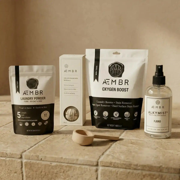 AEMBR Ultimate Laundry Kit with detergent, scoop, oxygen boost, dryer balls, and linen spray in a natural setting.