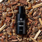 AEMBR ALKYMIST® Luxe Amber Oud multi-use fragrance bottle with elegant label and amber-colored liquid inside.