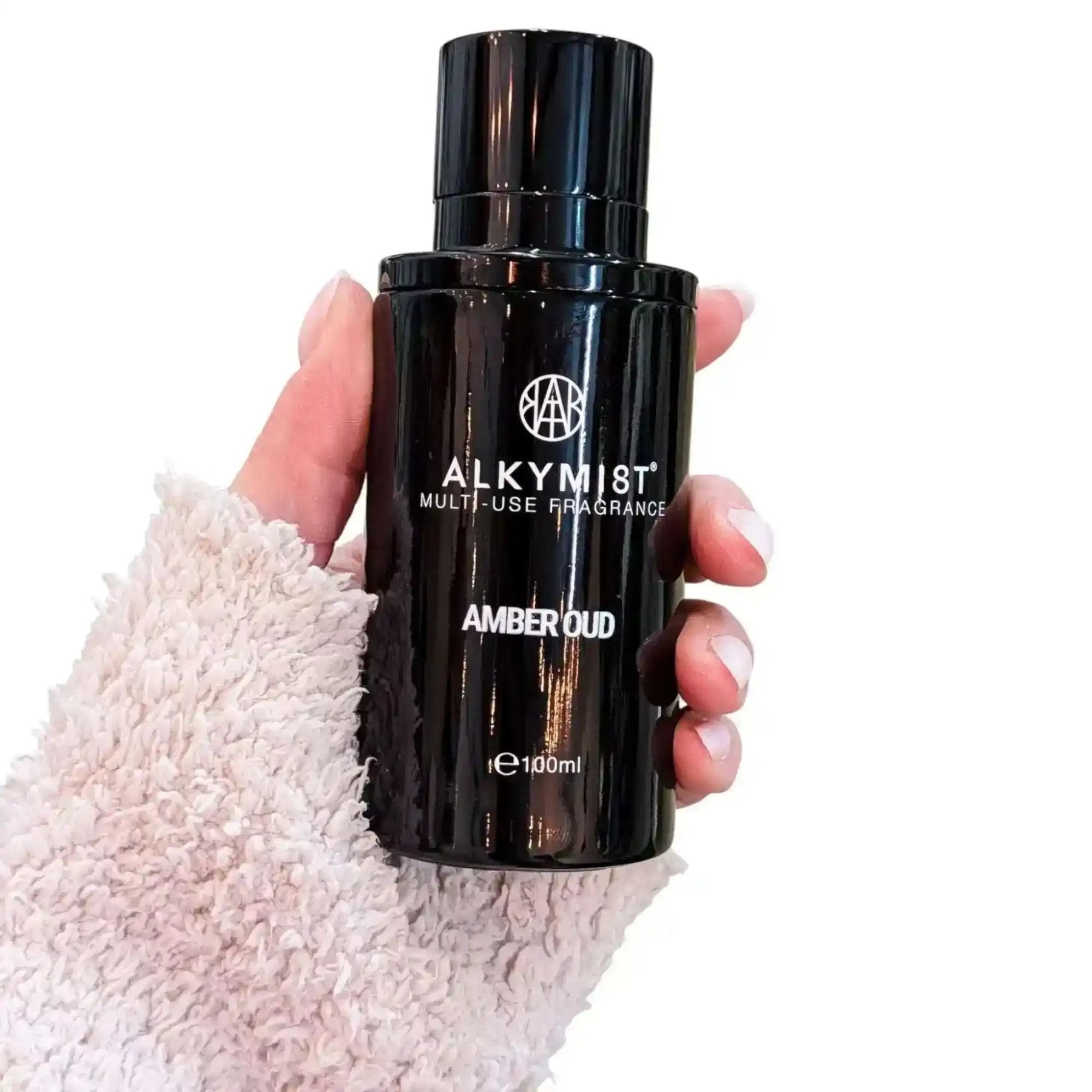 AEMBR ALKYMIST® Luxe Amber Oud multi-use fragrance bottle with elegant design and amber-colored liquid.