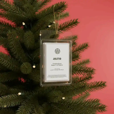 AEMBR Juletid Wax Melts in a clear plastic container with colorful festive packaging, showcasing seasonal scent and product branding.