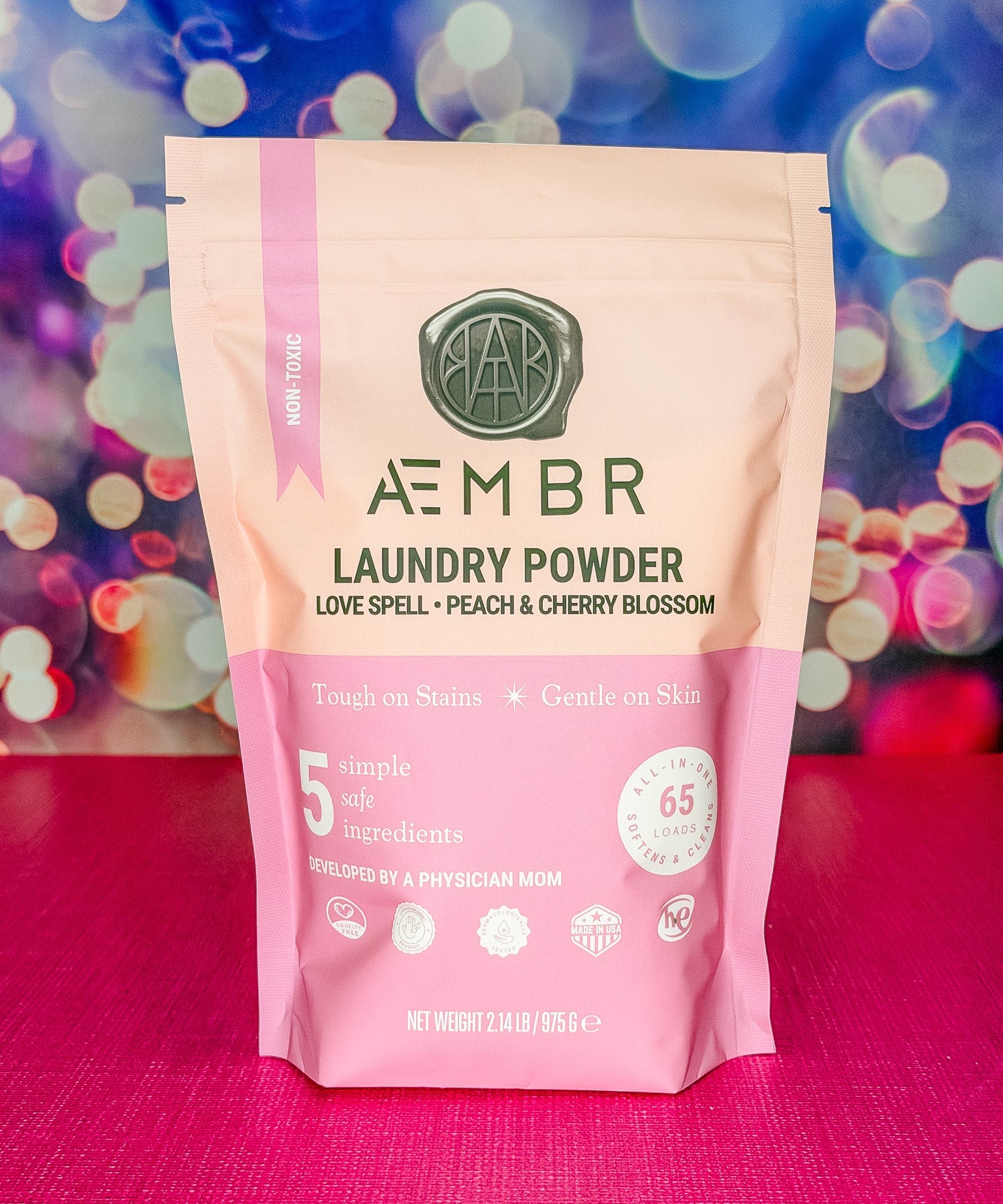 Package of AEMBR laundry powder with a colorful bokeh background