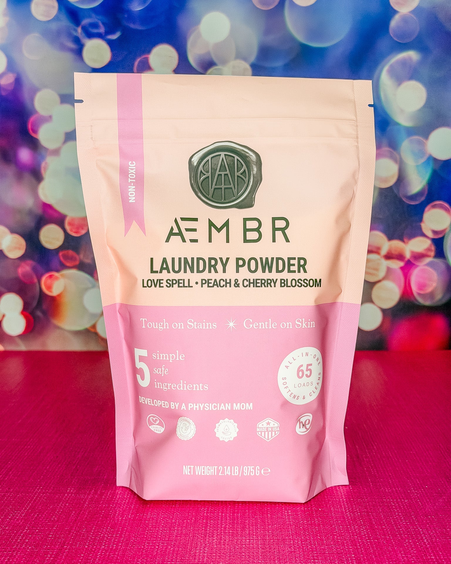Package of AEMBR laundry powder with a colorful bokeh background