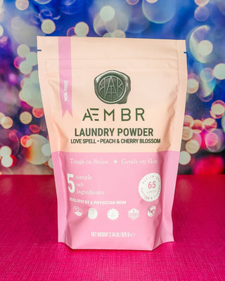 Package of AEMBR laundry powder with a colorful bokeh background