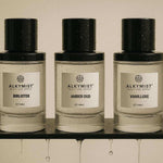 AEMBR Alkymist non-toxic multi-use sprays Bibliotek, Amber Oud, and Vanilluxe on a black shelf