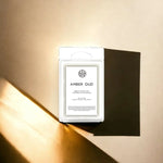 AEMBR Amber Oud coconut wax melt package on warm beige background, non-toxic home fragrance.