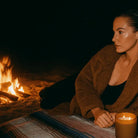 AEMBR citron salt candle lit at night by a woman on a beach near a bonfire