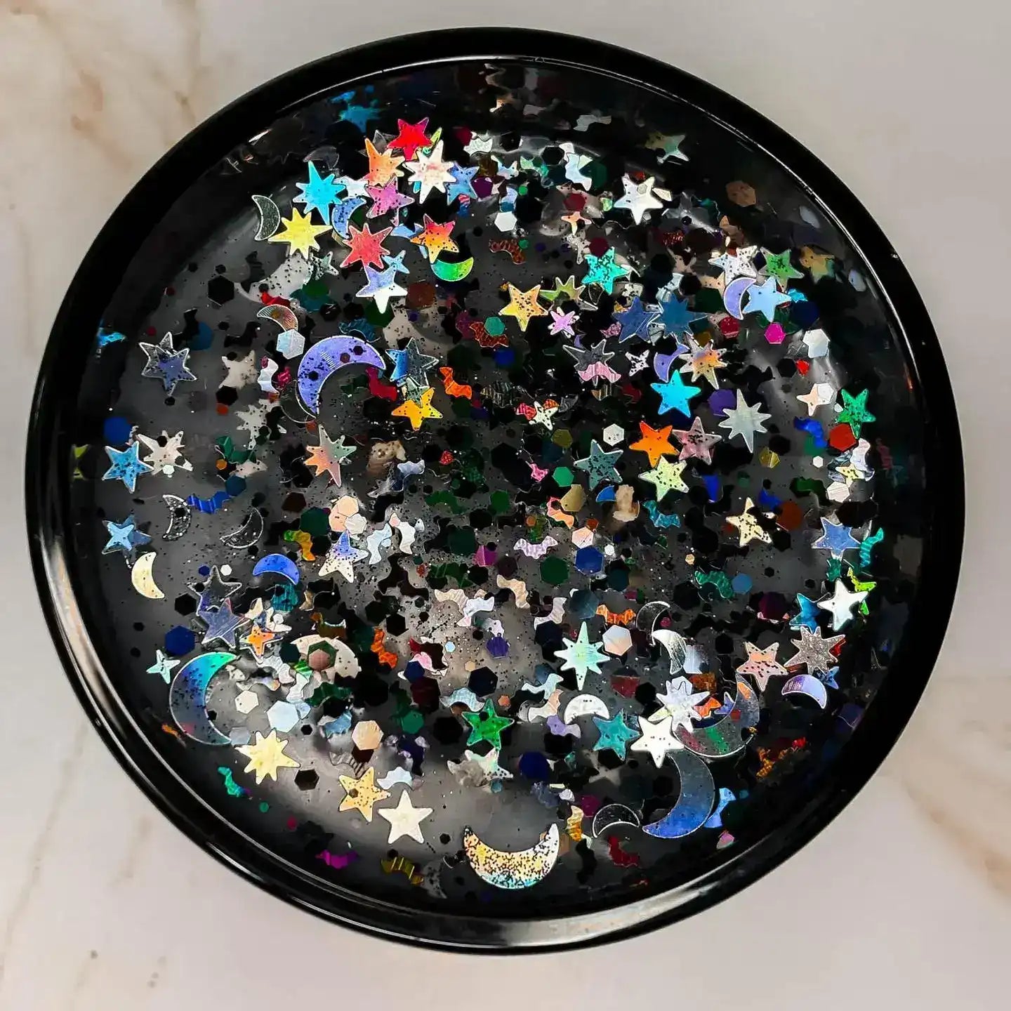 AEMBR black candle with holographic star and moon glitter on marble surface