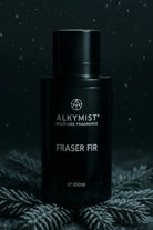 AEMBR ALKYMIST Fraser Fir multi-use fragrance bottle on frosted pine with dark background