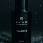 Black fragrance bottle labeled 'Alkymist Fraser Fir' on a dark background with foliage.