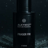 Black fragrance bottle labeled 'Alkymist Fraser Fir' on a dark background with foliage.
