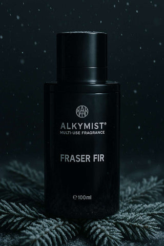 Black fragrance bottle labeled 'Alkymist Fraser Fir' on a dark background with foliage.