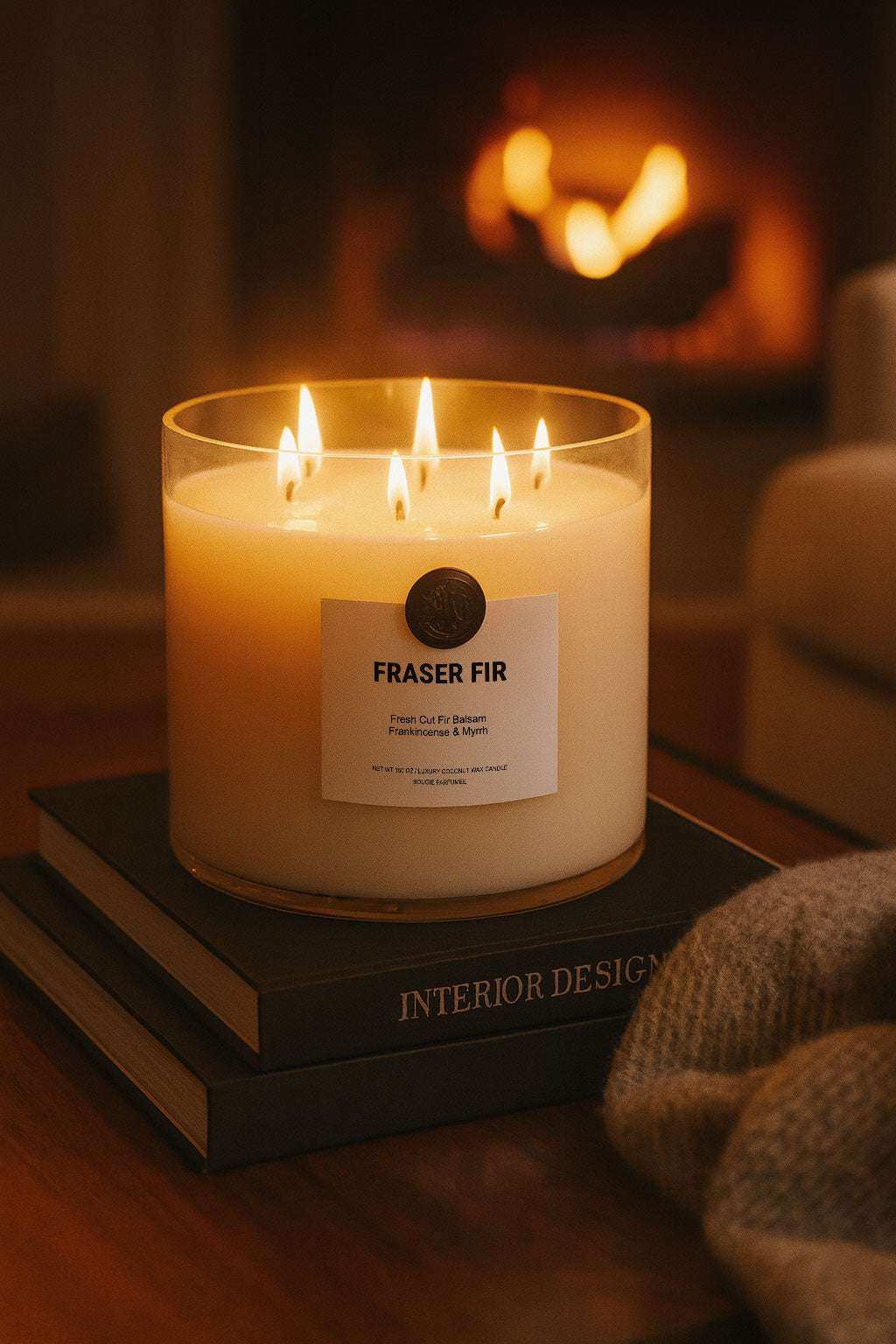 AEMBR Fraser Fir candle with multiple flames on stacked books, cozy fireplace in background