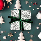 AEMBR holiday gift box with botanical wrap and green velvet ribbon, surrounded by festive decor.