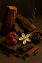 AEMBR home fragrance ingredients with wood, resin, white flower, cloves, and incense sticks.