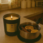 AEMBR Hygge candle burning beside mulled wine with orange and cinnamon in cozy kitchen