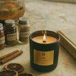 AEMBR Hygge candle burning on marble with dried orange slices, cinnamon sticks, and spice jars