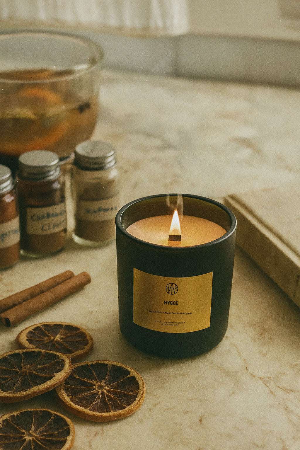 Candle with a label on a table with cinnamon sticks and dried oranges