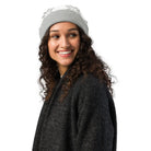 Woman wearing a gray AEMBR knitted beanie with white snowflake pattern on a white background